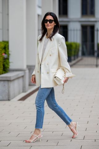 A street styler wearing blue denims and a white blazer