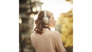 A woman wearing a pair of Bose QC 35 II while standing outside.