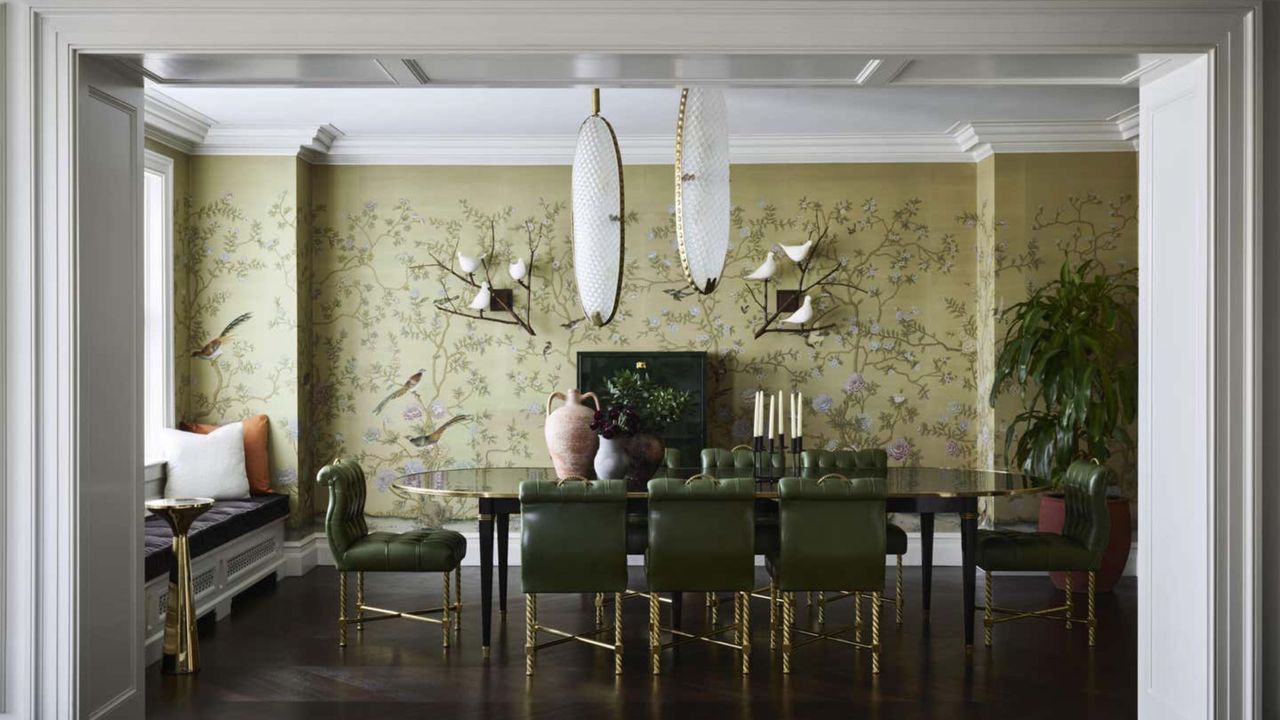 dining room with green floral wallpaper, statement pendant light, green and gold chairs, and window seat