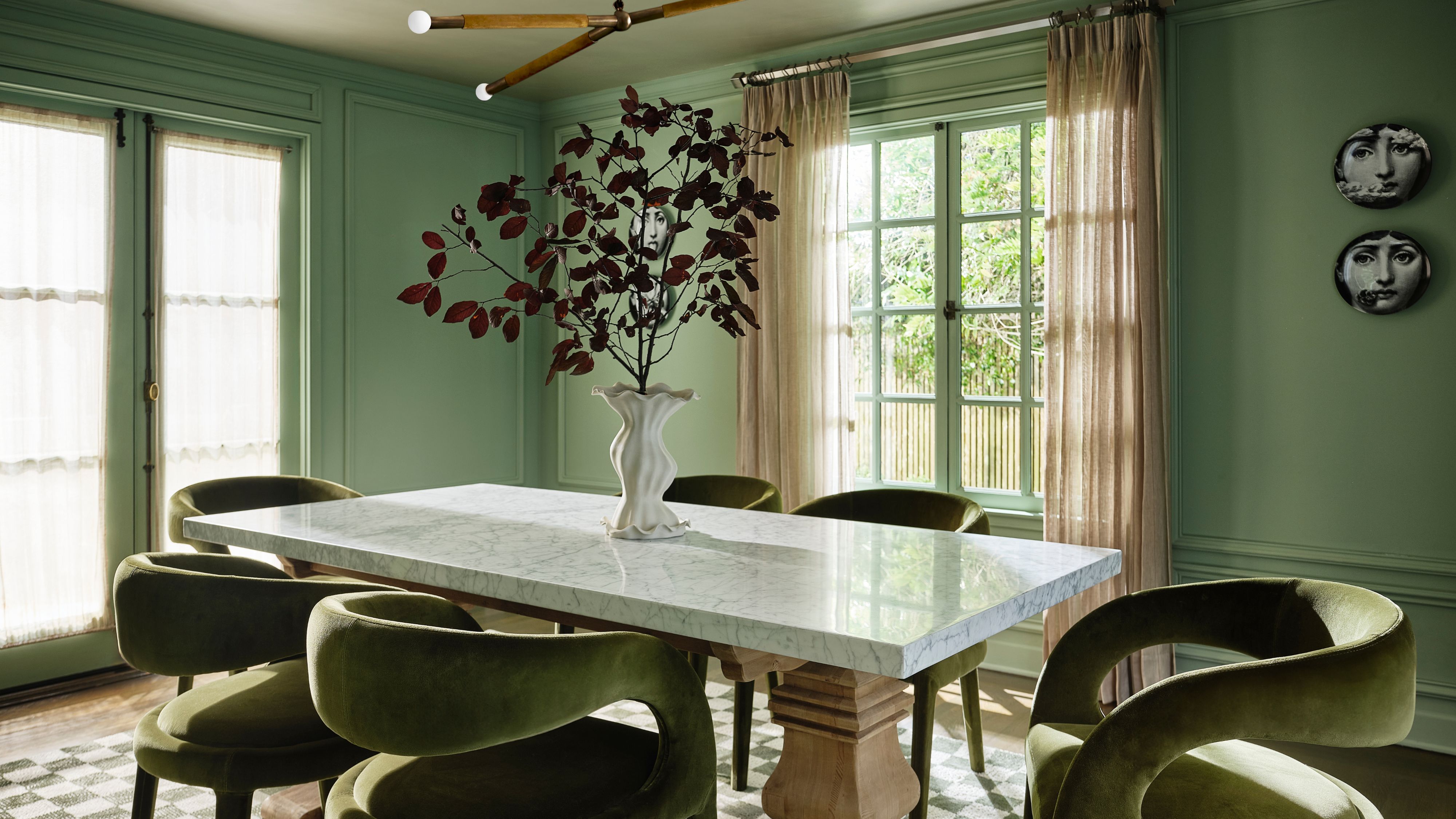 San Francisco Tudor dining room by Atelier Oleana featuring green walls and chairs, alongside a double pedestal dining table and checkered rug.
