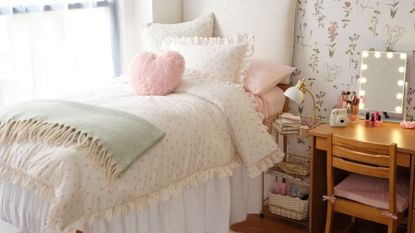 White bed with pink cushion and green blanket