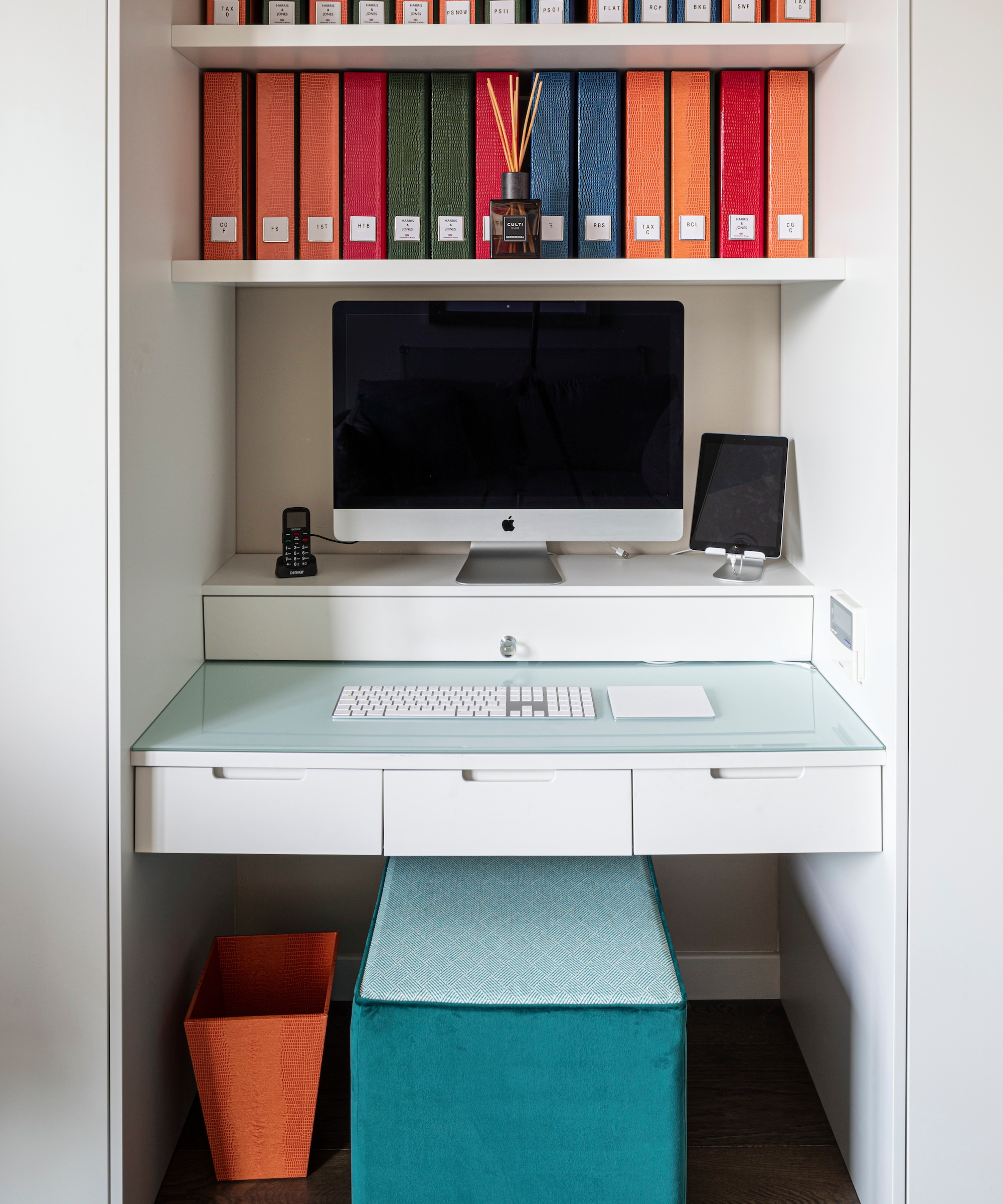 white cupboard designed as work space with built in desk and drawers, shelves, coloured files and blue stool