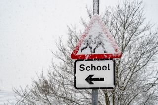 A school road sign covered in snow