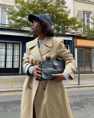 woman wearing a camel coat, black bag and baseball cap