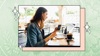 A woman seated at her desk reviews her finances on a mobile app.