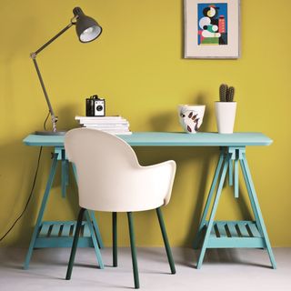 green desk with white chair and yellow walls