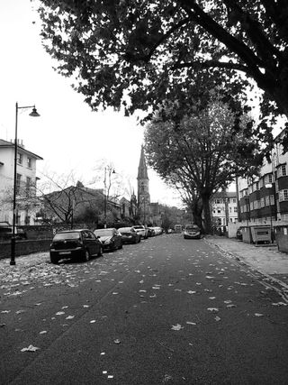 black and white photo of a street with a church at the end