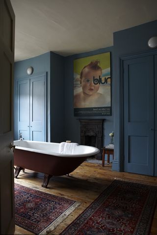 Bathroom with dark blue panelling and bathtub in centre