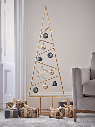 A gold-colored metal Christmas tree with blue and gold bauble decor