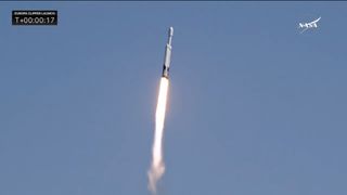 closeup of a white rocket climbing into a blue sky