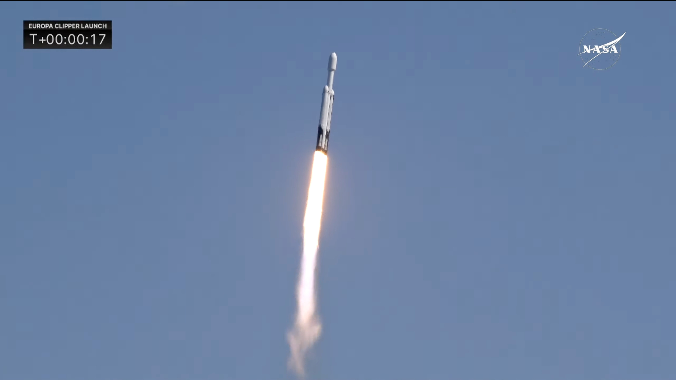 Close-up of a white rocket climbing into a blue sky