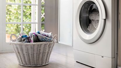  View of laundry room with washing machine and laundry basket with dirt clothes