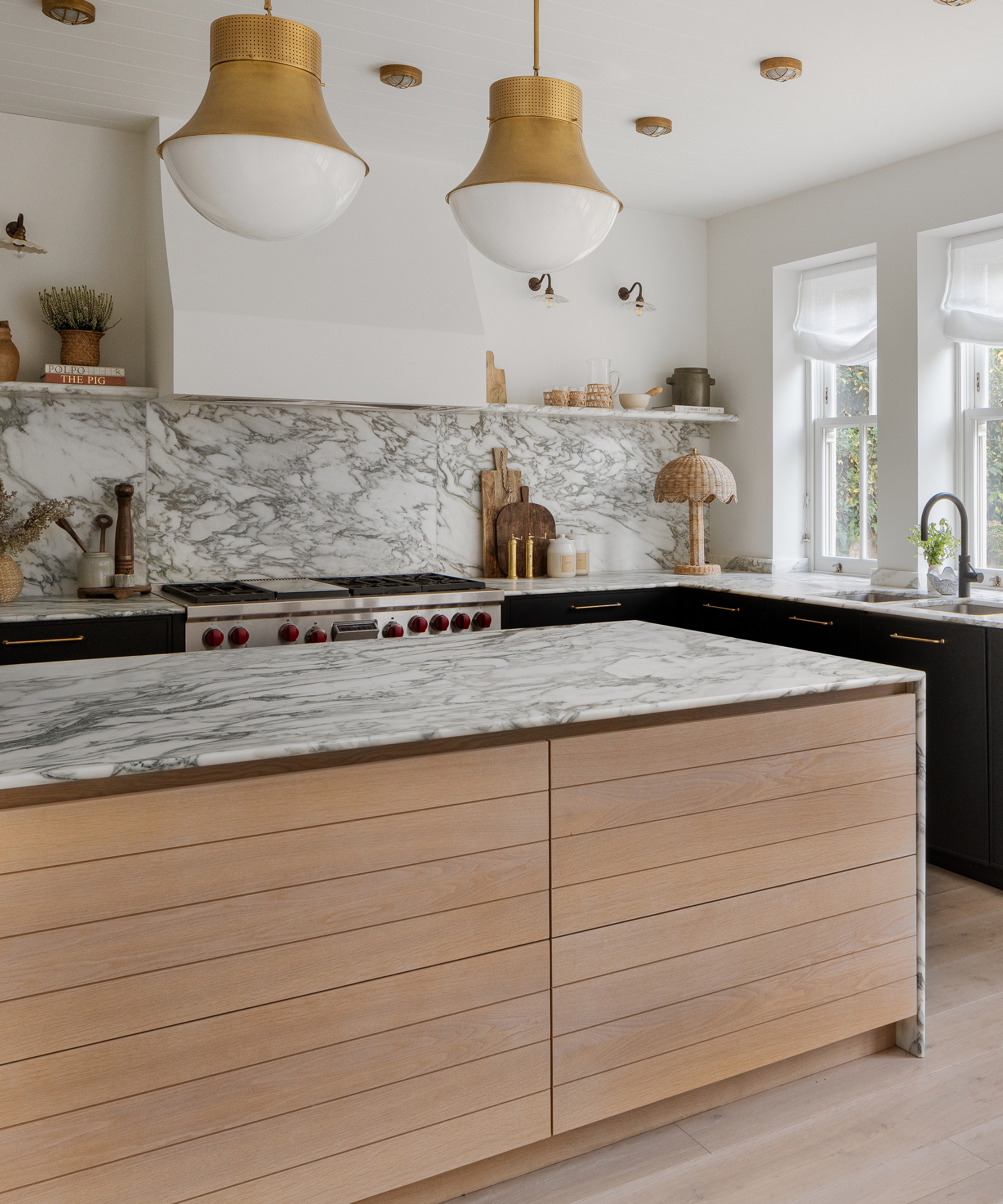 A navy and white kitchen with a wooden island and layered lighting