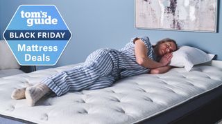 A person lies in a side sleeping position on the Helix Midnight Luxe Mattress. A Tom&#039;s Guide Black Friday mattress deals graphic (left)