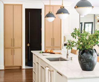 kitchen with white walls and wooden cupboards with white island and three glass pendant lights