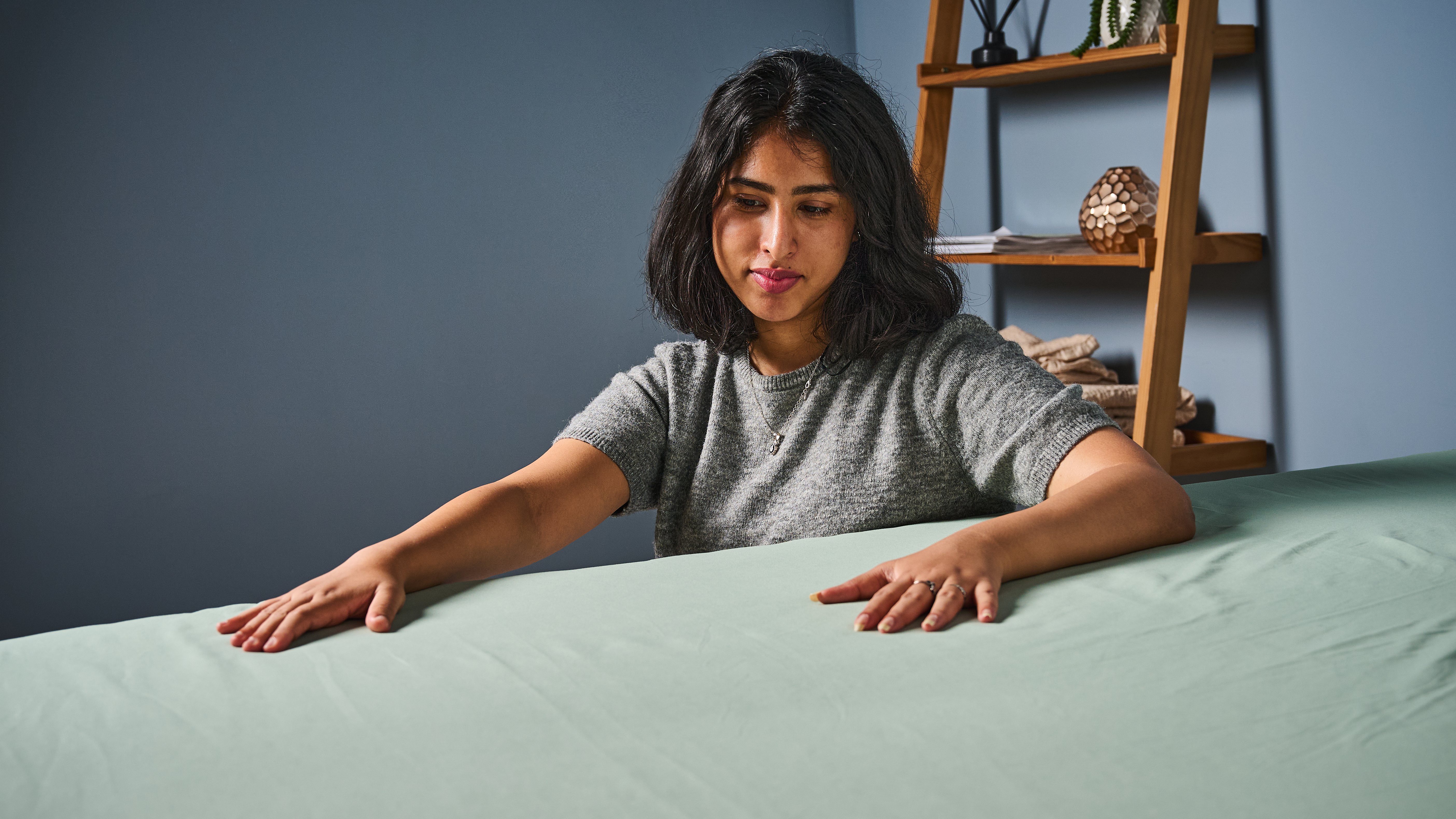 TG bedding writer testing the Utopia Bedding sheet set in our sleep studio by placing the hands on the fabric checking breathability and softness