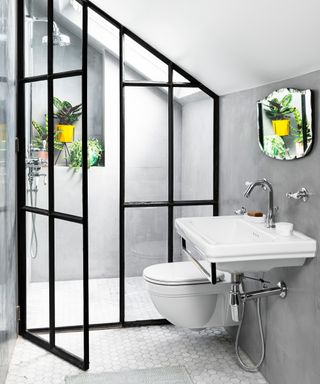A crittall-style shower screen in a small bathroom with a skylight and pale scheme
