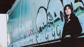 Tuk Smith leaning against a railway wagon covered in graffiti