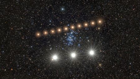 A series of bright golden dots form a diagonal line in the center of a starry night, with three larger whiter dots at the bottom of the image. 