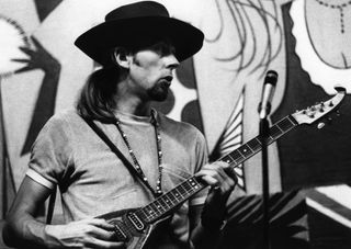 John Mayall, seated and playing guitar