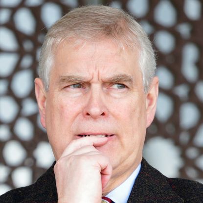 Prince Andrew wearing a black coat and looking anxious 