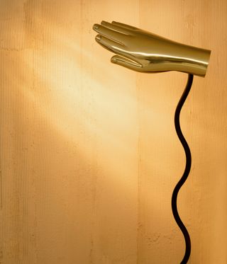 Gold lamp in the shape of a hand with curving black stem