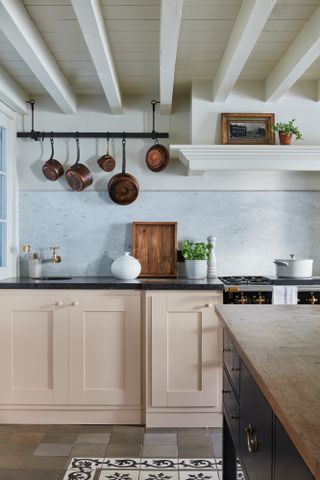 Pastel pink Shaker-style kitchen with black countertop and blue backsplash