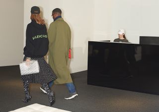 Two people in long clothes walking past reception desk