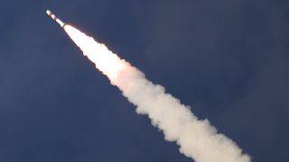 a red and white indian rocket launches into a dark blue sky