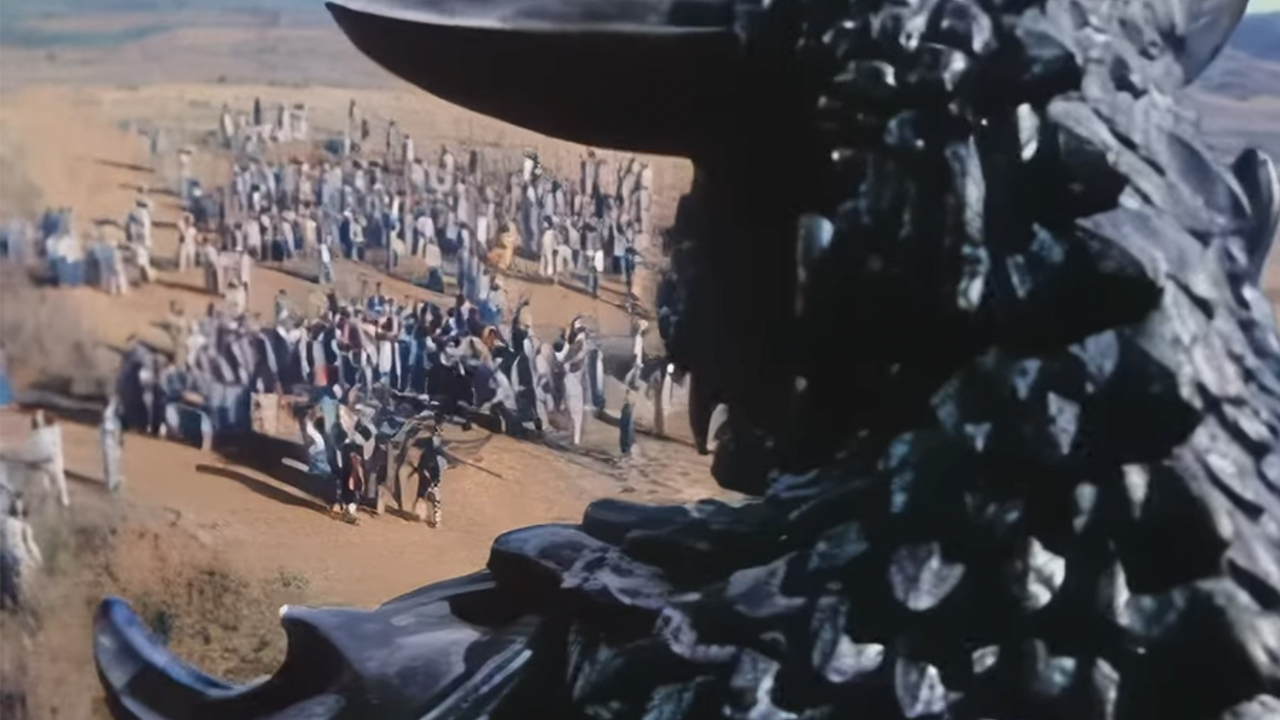 The monster from behind looking at a mass of people in Pulgasari