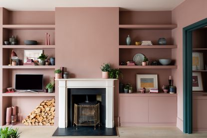 A pink painted living room in Farrow & Ball hues, with a white fireplace