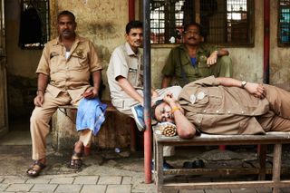 Workers sitting and sleeping outside a building