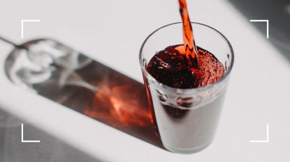 Red tart cherry juice being poured into a small glass with shadow behind it