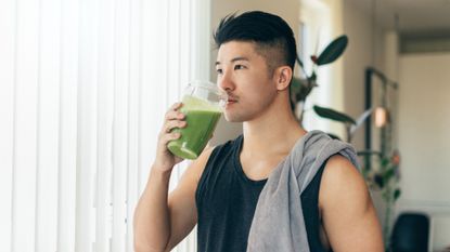 man drinking a green smoothie after a workout