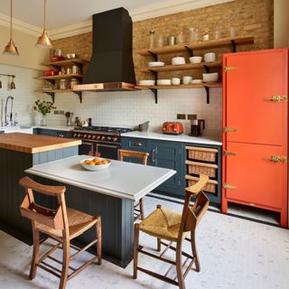 red and blue cabinets, exposed brick wall, blue island with wooden worktop