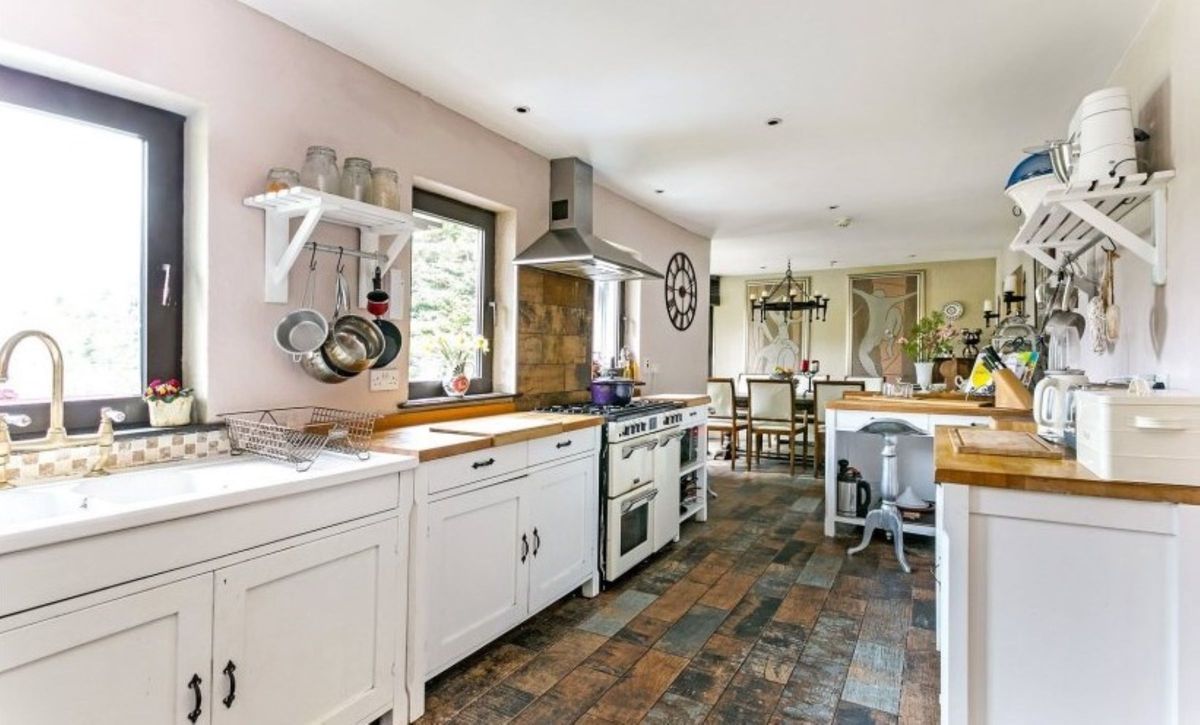 A white kitchen with grey tiled flooring and a dining room section