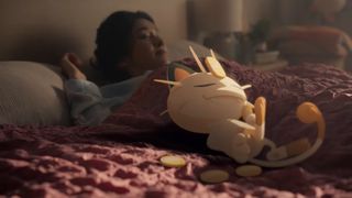 A still from the Pokémon Sleep trailer showing Meowth sleeping on someone's bed