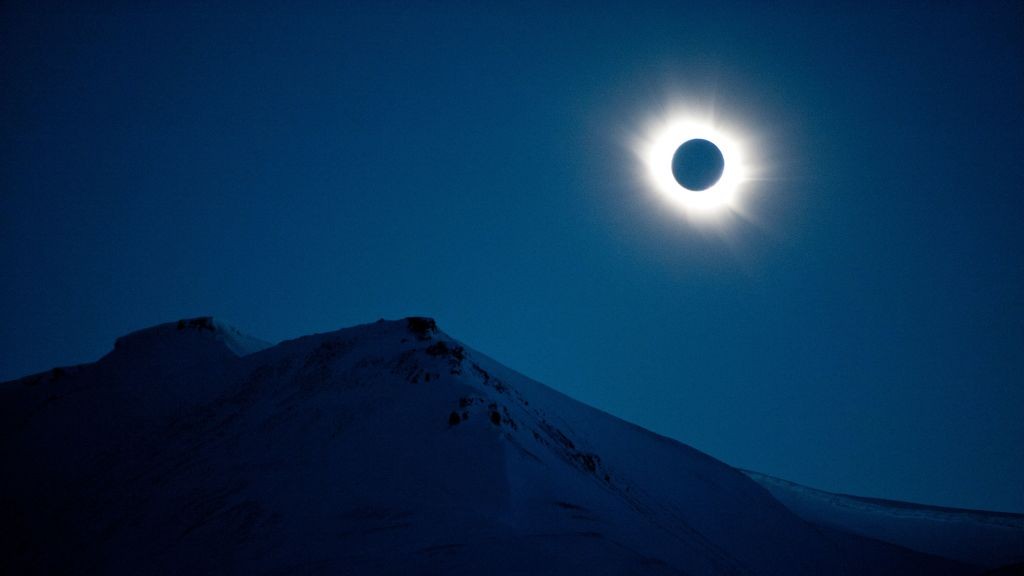 Um eclipse solar total pode ser visto em 20 de março de 2015 em Longyearbyen, Svalbard, Noruega. O Sol aparece como uma mancha preta com um halo branco brilhante ao seu redor.