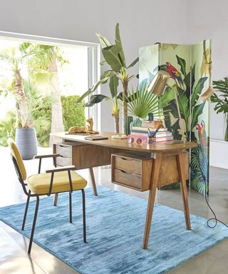 Home office with jungle inspired room divider and large potted banana plant.