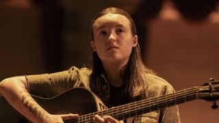 Ellie playing acoustic guitar on theatre stage in The Last Of Us Season 2 "Feel Her Love"