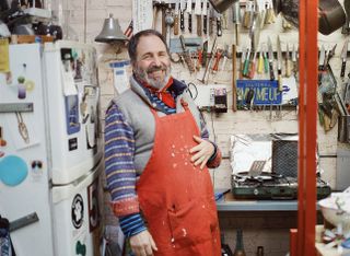 A portrait of Peter Shire laughing, photographed in his studio.