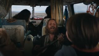 Rhys Ifans' unnamed character strums a guitar in a camper van in Venom: The Last Dance