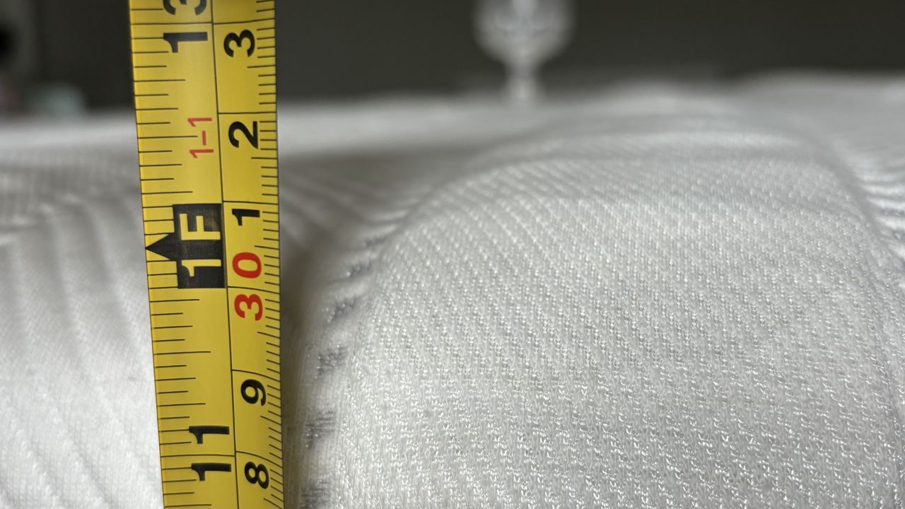 A tape measuring the height of the Leesa Legend Hybrid Mattress