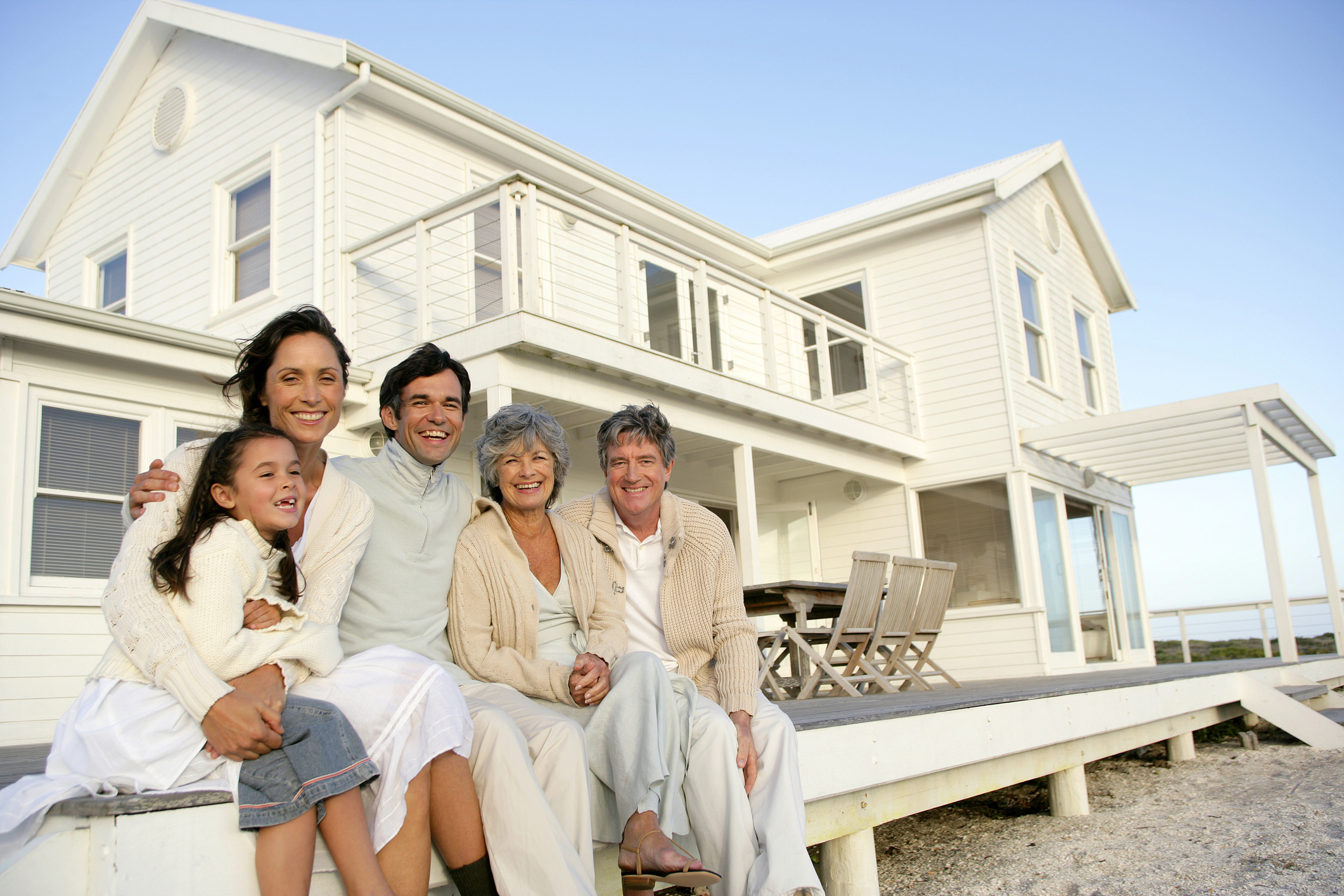 A multigenerational family sitting on the porch of a beach house.