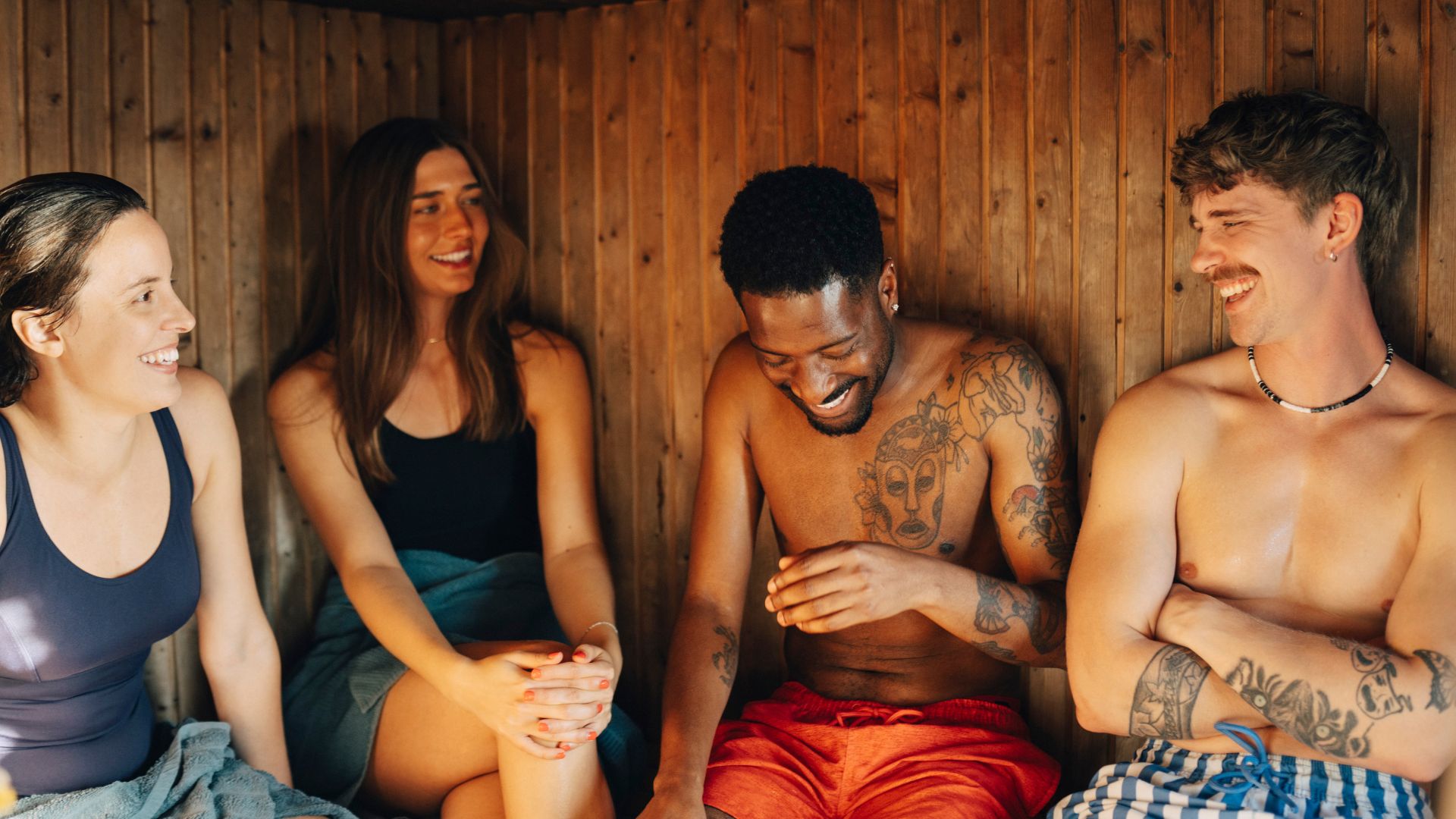 Two women and two men sitting in a sauna laughing