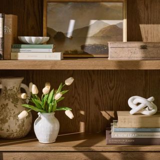 A small white vase on a large wooden bookshelf