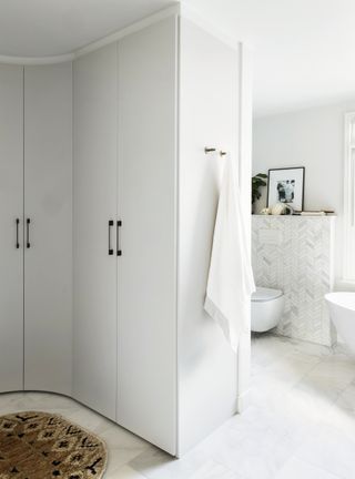 White bathroom with storage and white freestanding tub