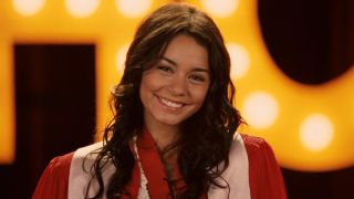 Vanessa Hudgens in High School Musical 3 smiling at the camera in a graduation robe. 