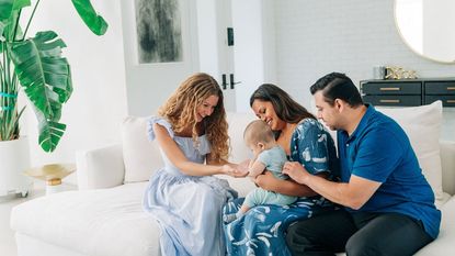 Expecting parents meet with a surrogate, who is holding sonogram photos.