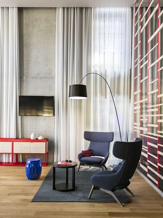 Seating area featuring two navy, wing-back chairs, circular coffee table and a blue stool